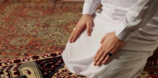 Person kneeling on a prayer rug in traditional attire