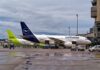 Two airplanes parked at an airport with ground service vehicles nearby