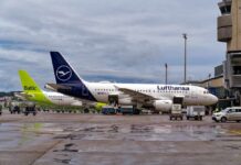 Two airplanes parked at an airport with ground service vehicles nearby