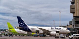 Two airplanes parked at an airport with ground service vehicles nearby