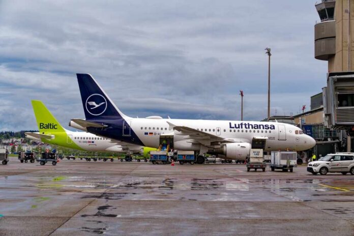 Two airplanes parked at an airport with ground service vehicles nearby