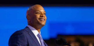A confident speaker in a suit smiling while addressing an audience