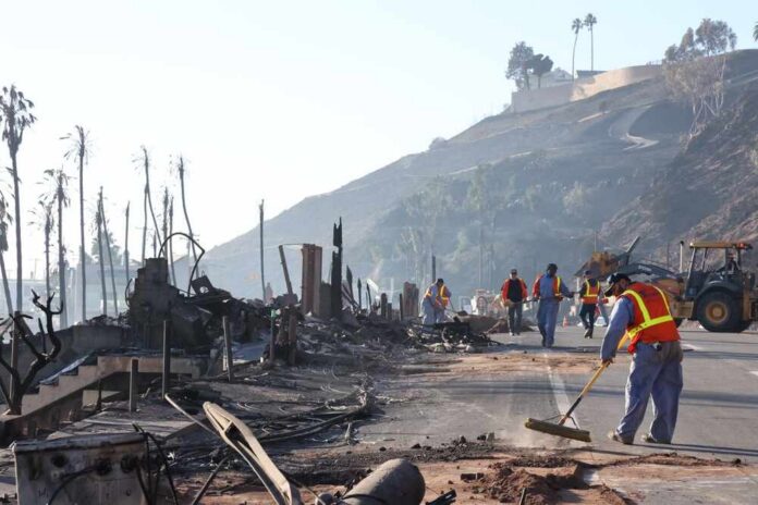 Workers cleaning up debris from a wildfire-affected area