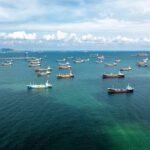Aerial view of numerous cargo ships anchored in a blue ocean