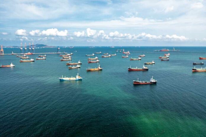 Aerial view of numerous cargo ships anchored in a blue ocean