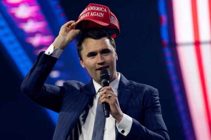 Man in a suit holding a red cap while speaking into a microphone