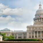 Capitol building with dome under partly cloudy sky.