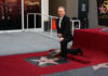 man in a suit kneeling by a Hollywood Walk of Fame star