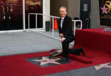 man in a suit kneeling by a Hollywood Walk of Fame star