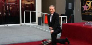 man in a suit kneeling by a Hollywood Walk of Fame star