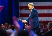 man in blue suit speaking at a podium