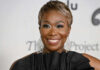 Person smiling wearing large earrings and a black top