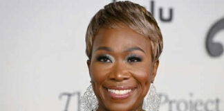 Person smiling wearing large earrings and a black top