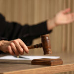 Judge's hand striking a wooden gavel on a block
