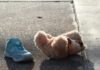 Teddy bear and blue child’s shoe on a sunlit sidewalk