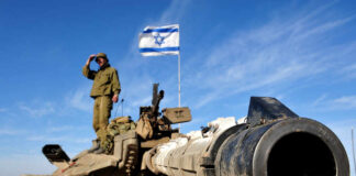 Soldier saluting from atop a tank with an Israeli flag in the background