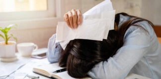 Woman with head on desk amid bills and credit cards