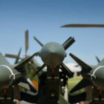 Close-up view of military missiles with aircraft in the background
