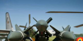 Close-up view of military missiles with aircraft in the background