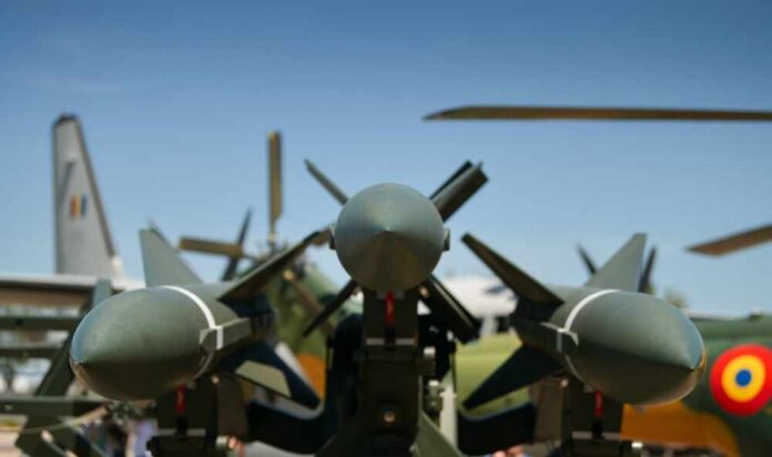 Close-up view of military missiles with aircraft in the background