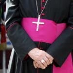 A religious figure in ceremonial attire with a cross necklace
