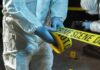 forensic investigators unrolling yellow barrier tape at night