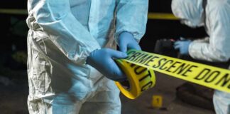 forensic investigators unrolling yellow barrier tape at night