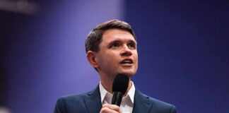 A man in a suit speaking into a microphone during a presentation