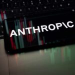 Smartphone displaying the word 'ANTHROPIC' over a background of financial graphs