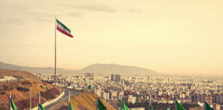 View of Iranian flags with a city and mountains in the background