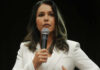 Woman in white suit speaking into a microphone