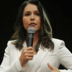 Woman in white suit speaking into a microphone