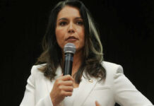 Woman in white suit speaking into a microphone
