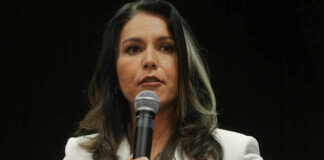 Woman in white suit speaking into a microphone