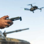 Hands holding a drone controller with quadcopter in flight