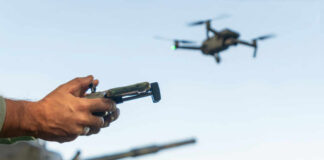 Hands holding a drone controller with quadcopter in flight
