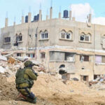 Soldier crouching near damaged building in urban area