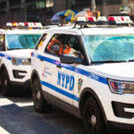 Parked row of NYPD police vehicles with flashing lights.