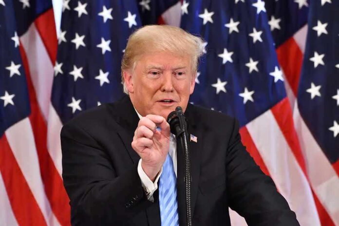 man speaking at a podium with American flags behind him