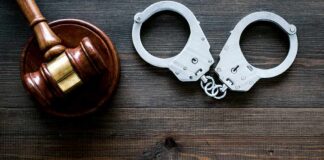 Gavel and handcuffs on wooden table