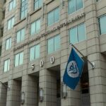 U.S. government building facade with American and blue departmental flags