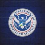 U.S. Department of Homeland Security seal on a blue brick wall