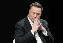 Elon’s AI Empire Faces A New Challenge man in a suit with hands clasped thoughtfully