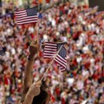 Fans waving American flags in a crowded stadium
