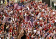 Fans waving American flags in a crowded stadium