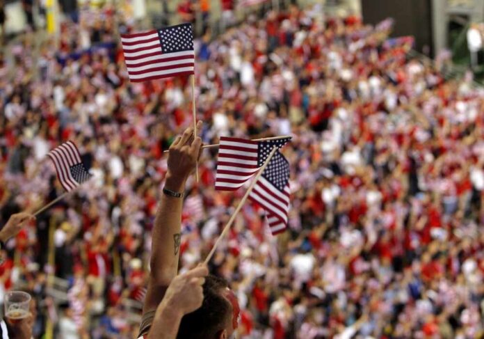 Fans waving American flags in a crowded stadium