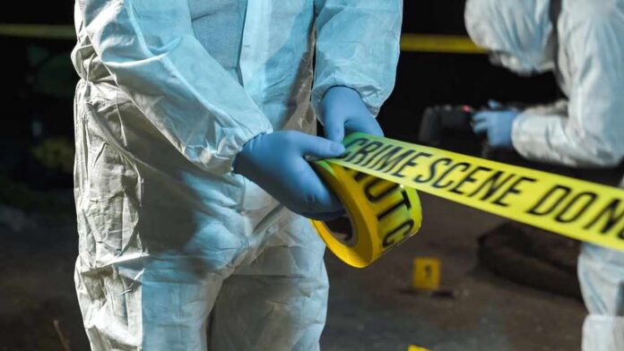 forensic investigators unrolling yellow barrier tape at night