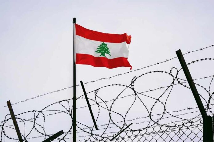 The,Concept,Of,Sanctions,Pressure,On,The,Lebanon,Government.,Lebanon Lebanese flag waving next to barbed wire fence