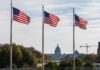 Three American flags waving in front of the Capitol building