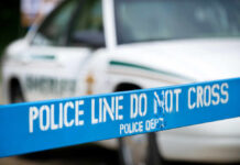 Police line marked with caution tape in front of a police vehicle